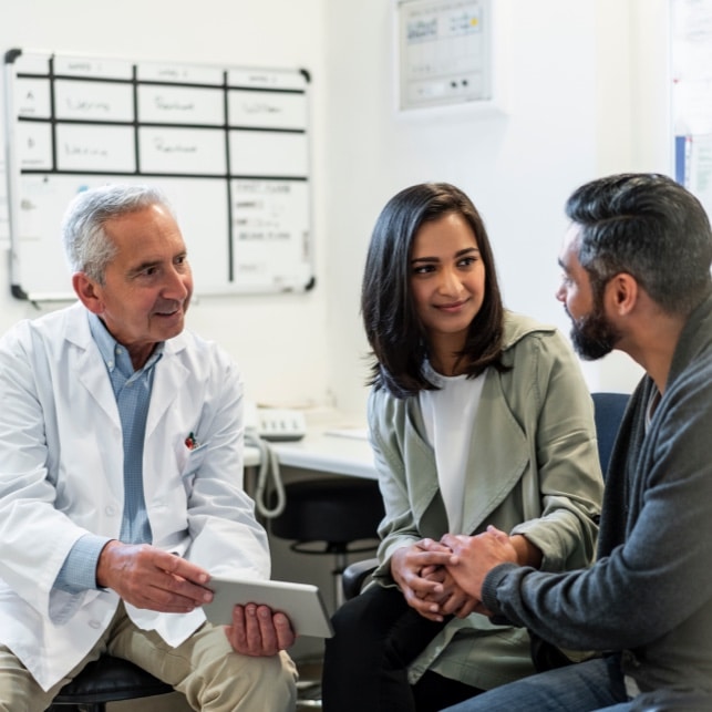 Doctor Discussing With Couple Over Digital Tablet