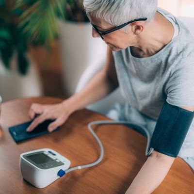 Woman using remote patient monitoring device to check blood pressure readings on phone